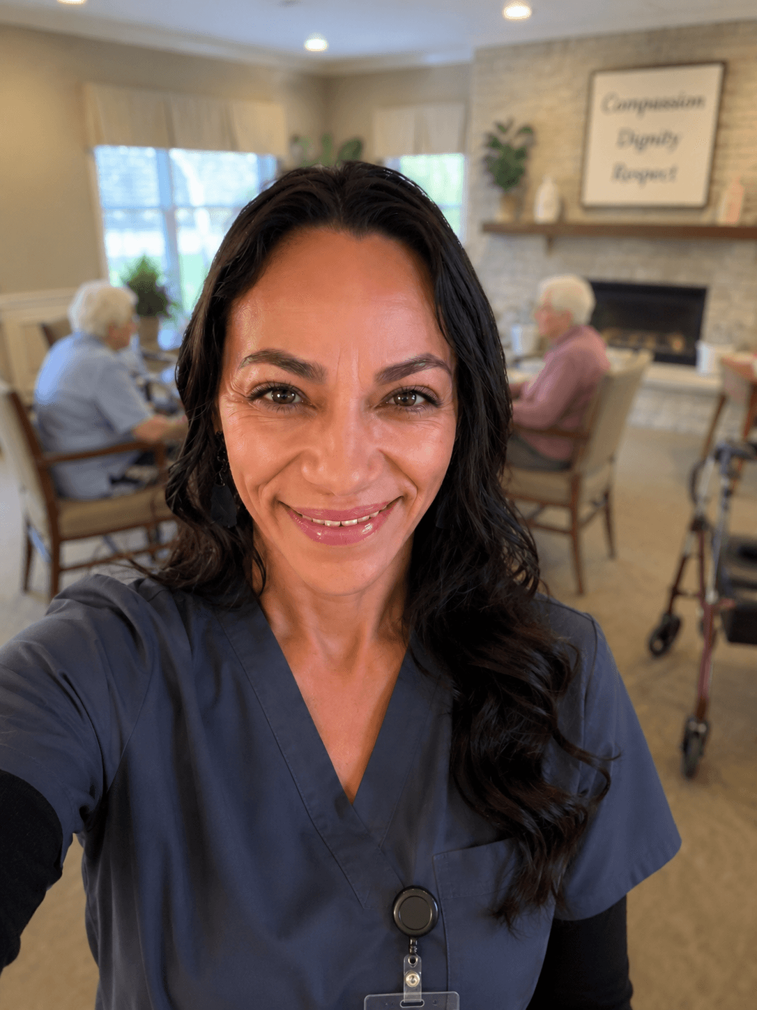 Smiling healthcare professional in blue scrubs with elderly residents in a senior living facility.